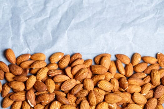 Delicious roasted sweet almonds lie in a large heap, nuts close-up.