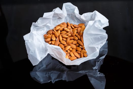 Delicious roasted sweet almonds lie in a large heap, nuts close-up.