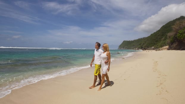 Beautiful couple embracing each other stands on the beach and looks at the sea.Relationships, Beach, couple on romantic travel honeymoon vacation summer holidays romance. Young happy lovers. Travel concept. Bali.