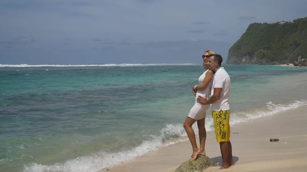 Beautiful couple embracing each other stands on the beach and looks at the sea.Relationships, Beach, couple on romantic travel honeymoon vacation summer holidays romance. Young happy lovers. Travel concept. Bali.