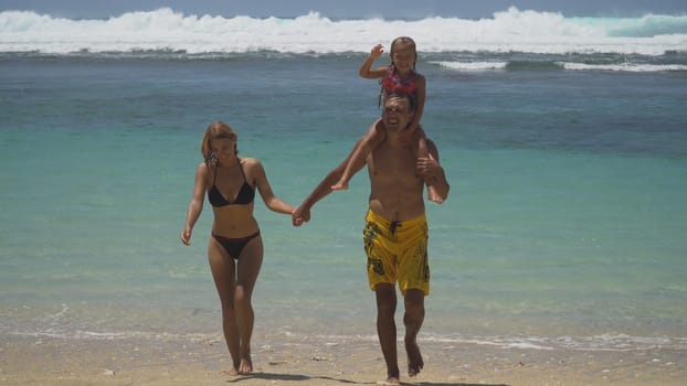 Happy beautiful family with child walking together on tropical beach during summer vacation. Bali. Family of three having fun on tropical beach. Travel concept. Family relationships