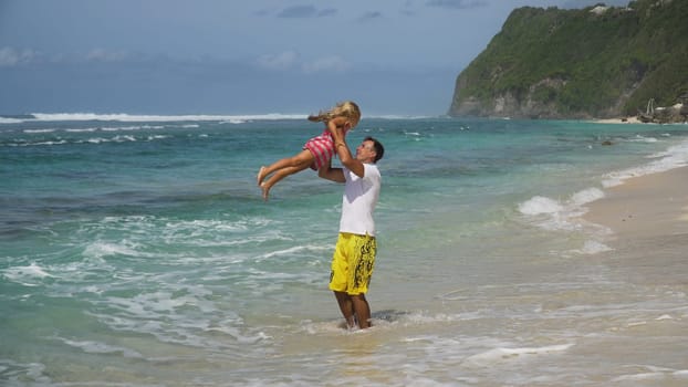 Happy beautiful family with child walking together on tropical beach during summer vacation. Bali. Family of three having fun on tropical beach. Travel concept. Family relationships