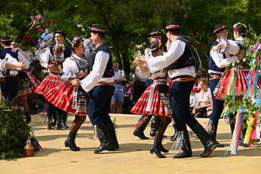 Brno - Bystrc, Czech Republic, 24 June, 2023. Traditional festivities of the feast of the feast in the Czech Republic. Food and drink festival. Girls and boys dancing in beautiful colourful traditional costumes. An old Czech custom of celebrating in villages. 