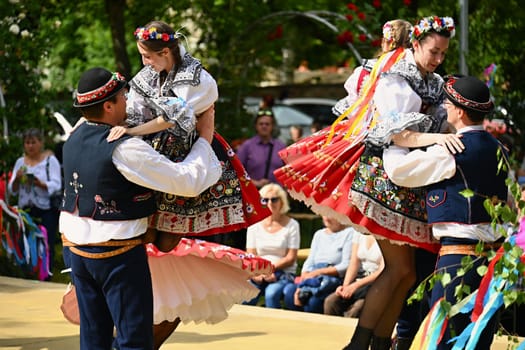 Brno - Bystrc, Czech Republic, 24 June, 2023. Traditional festivities of the feast of the feast in the Czech Republic. Food and drink festival. Girls and boys dancing in beautiful colourful traditional costumes. An old Czech custom of celebrating in villages. 