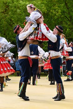 Brno - Bystrc, Czech Republic, 24 June, 2023. Traditional festivities of the feast of the feast in the Czech Republic. Food and drink festival. Girls and boys dancing in beautiful colourful traditional costumes. An old Czech custom of celebrating in villages. 