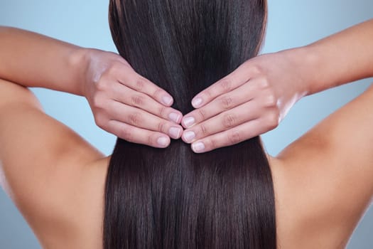 Beauty salon, hair and back of woman in studio for haircare, cosmetics or shampoo product on blue background. Girl, hands and touch healthy, natural and glowing texture on head or cosmetic extensions.