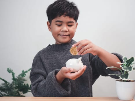 A boy putting coins into piggy bank. Learning financial responsibility and projecting savings. savings concept. investment concept.