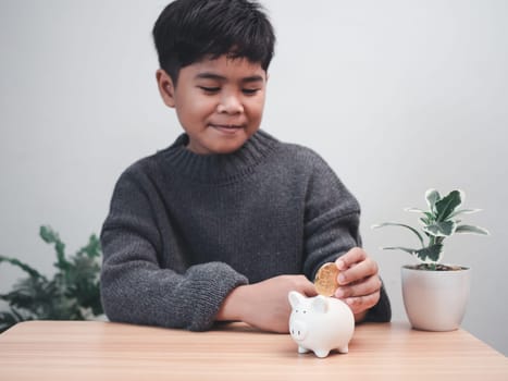 A boy putting coins into piggy bank. Learning financial responsibility and projecting savings. savings concept. investment concept.