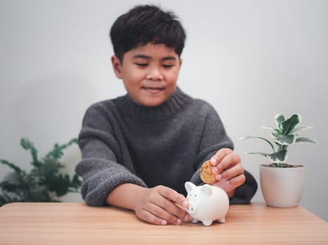 A boy putting coins into piggy bank. Learning financial responsibility and projecting savings. savings concept. investment concept.