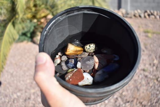 Hand Holding Rock Tumbler Barrel Full of Assorted Polished Stones on Step 3 Grit . High quality photo