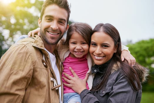 Family, happy hug and park portrait with a mom, dad and girl together with happiness and smile. Outdoor, face and vacation of a mother, father and young kid with bonding, parent love and child care.