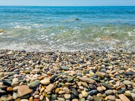Scenic view of empty pebble sea coast during sunny day