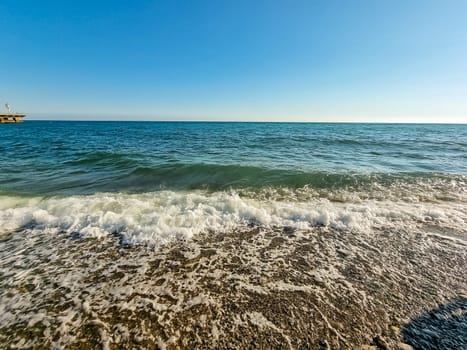 Scenic view of empty pebble sea coast during sunny day