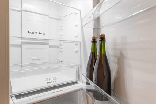 Close-up of two bottles standing in a refrigerator on a door shelf in an empty refrigerator. The concept of alcoholic drinks or alcoholism.