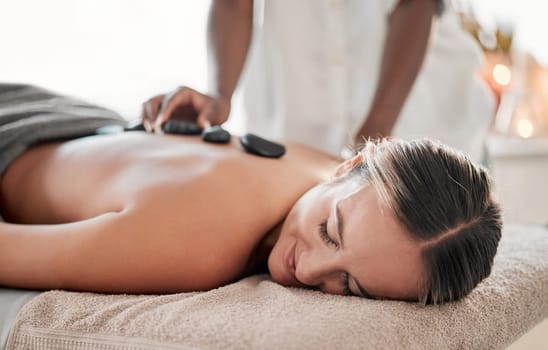 Woman, hot stones or back massage in spa to relax for zen, meditation or wellness physical therapy treatment in resort. Beauty, salon or happy female for luxury healthcare, rock or spiritual peace.