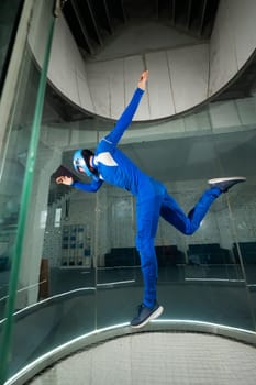 A man in overalls and a protective helmet enjoys flying in a wind tunnel. Free fall simulator.