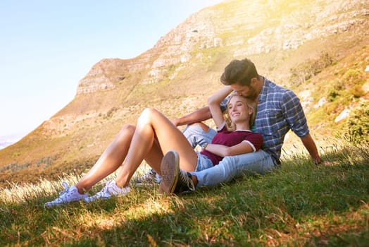 Relax, kiss and happy with couple in nature for carefree, bonding and affectionate. Happiness, date and romance with man and woman cuddle in grass field for summer break, love and mountains.