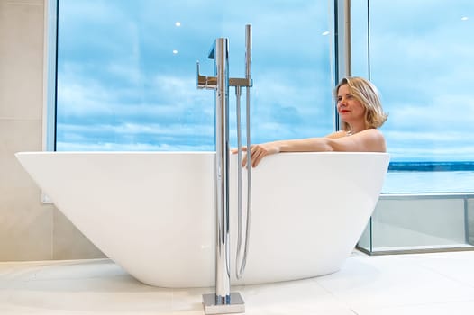 woman in freestanding white bath. Modern bathroom interior design. Beauty, healthy lifestyle concept. panoramic bathroom interior