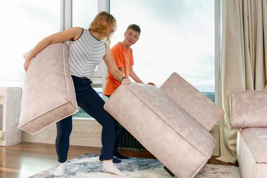 family rearranging furniture. Happy couple moving furniture in new apartment. Moving day, happy buyers. Positive smiling young couple moving furniture