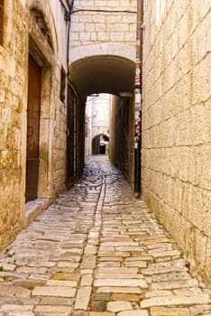 Narrow street with stone houses. Old houses and old narrow alley in Trogir, Croatia, Europe. Streets in old town.