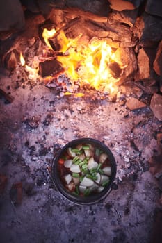 Dinner is served courtesy of a campfire. a traditional South African food being cooked by campfire outdoors