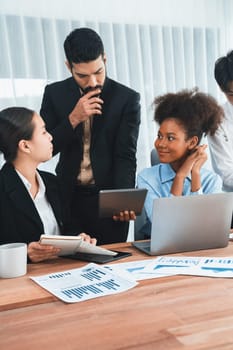 Multiracial analyst team use BI dashboard data to analyze financial report on meeting table. Group of diverse business people utilize data analysis by FIntech for success business marketing. Concord