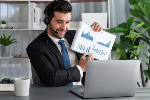 Business man wearing headphone present financial data or BI paper via laptop during online meeting. Remote work concept with virtual meeting presentation of effectiveness remote work. Fervent