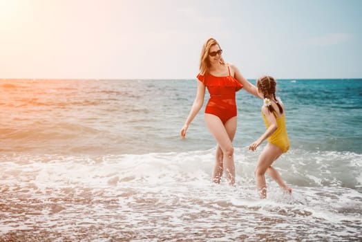 Happy loving family mother and daughter having fun together on the beach. Mum playing with her kid in holiday vacation next to the ocean - Family lifestyle and love concept.