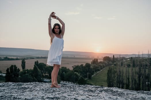 Romantic beautiful bride in white dress posing with sea and mountains in background. Stylish bride standing back on beautiful landscape of sea and mountains on sunset