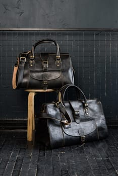 two different size black leather travel bags, indoors photo on black background