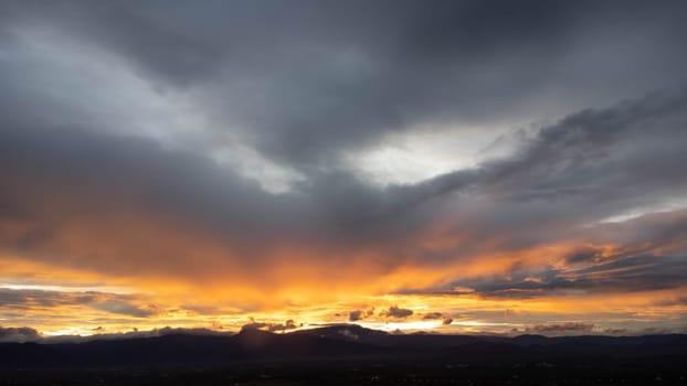 Real amazing sunrise or sunset sky with gentle colorful clouds. Beautiful natural sunset of the mountain range under colorful blue and orange sunset in the evening.