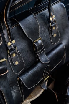 black leather travel bag, indoors photo on black background.