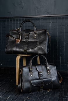 two different size black leather travel bags, indoors photo on black background