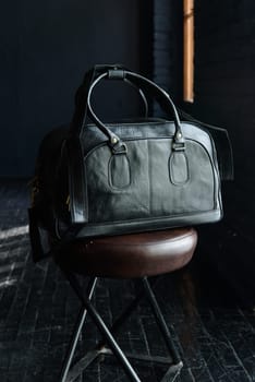 black leather travel bag, indoors photo on black background.