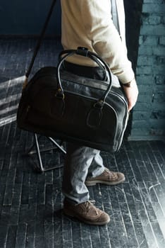 a man with a bag. black leather travel bag, indoors photo on black background.