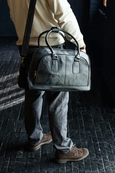 a man with a bag. black leather travel bag, indoors photo on black background.