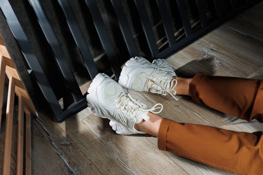 Collection of summer leather sneakers for women. Close-up of female legs in white sneakers. Women's summer sneakers with laces.