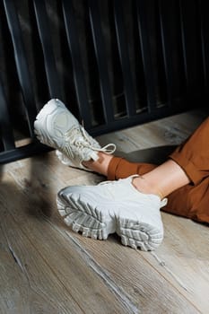 Collection of summer leather sneakers for women. Close-up of female legs in white sneakers. Women's summer sneakers with laces.