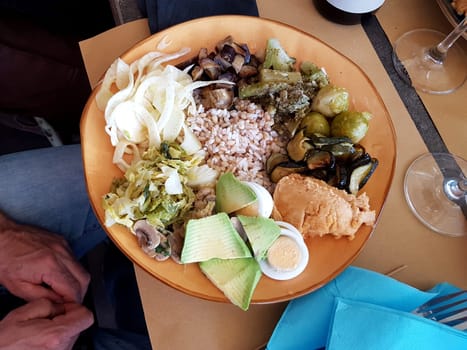 Vegetarian salad with cooked and raw vegetables, bulgur and hummus.