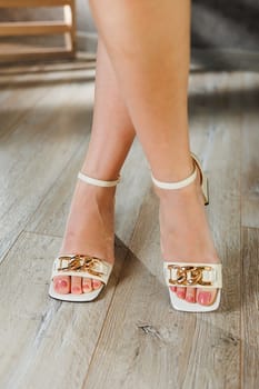 Collection of women's summer shoes. Beige leather women's sandals on slender legs and a beige heeled sandal. Women's summer elegant sandals.