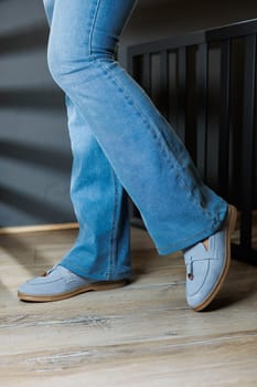 Slender female legs in jeans and blue loafers. Collection of summer women's shoes. Stylish women's shoes for summer