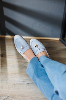 Slender female legs in jeans and blue loafers. Collection of summer women's shoes. Stylish women's shoes for summer