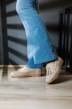 Slender female legs in jeans and beige loafers. Collection of summer women's shoes. Stylish women's shoes for summer
