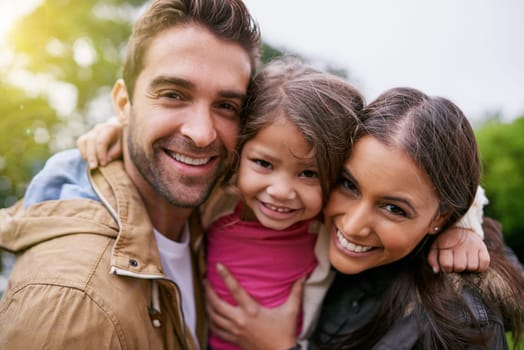 Family, closeup and park hug portrait with a mom, dad and girl together with happiness and smile. Outdoor, face and vacation of mother, father and kid with bonding, love and child care in nature.
