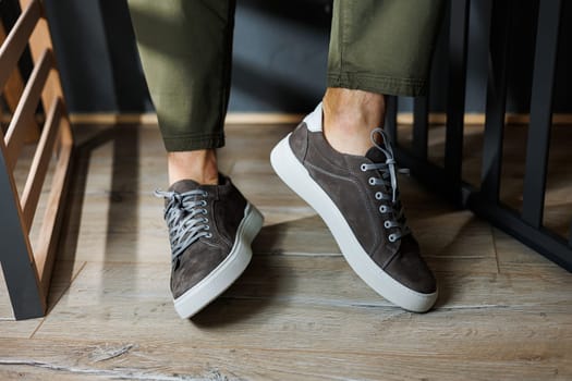 Close-up of male legs in pants and gray casual sneakers. Men's leather shoes. Collection of men's stylish summer shoes