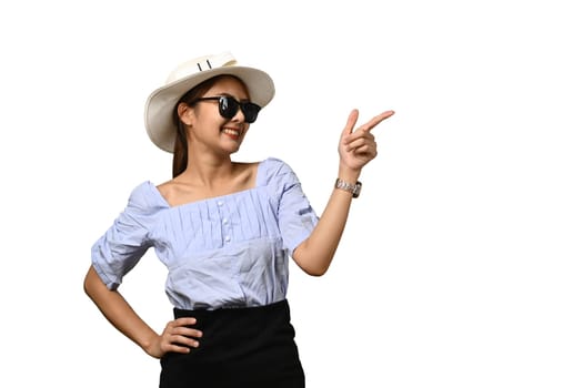 Happy woman in sunglasses and hat, pointing aside, shows space for your advertisement or promotional text isolated on white background.