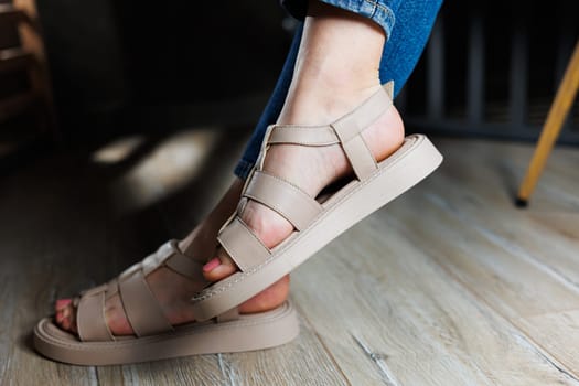 Summer women's sandals. Collection of women's leather summer sandals. Slender female legs in beige leather sandals without heels.