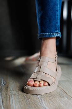 Summer women's sandals. Collection of women's leather summer sandals. Slender female legs in beige leather sandals without heels.