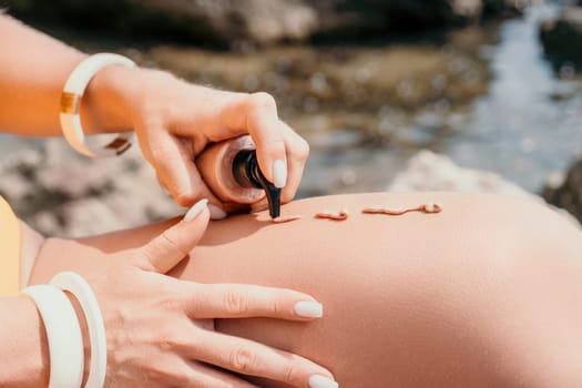 Sexy Woman in bikini apply sun protection cream on her smooth tanned legs. Skin care. Legs on the beach. Portrait of female in hat smearing moisturizing lotion. Sunblock concept.