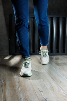 Sports shoes for women. Slender female legs in jeans and white stylish casual sneakers. Comfortable women's summer shoes. Casual women's fashion.